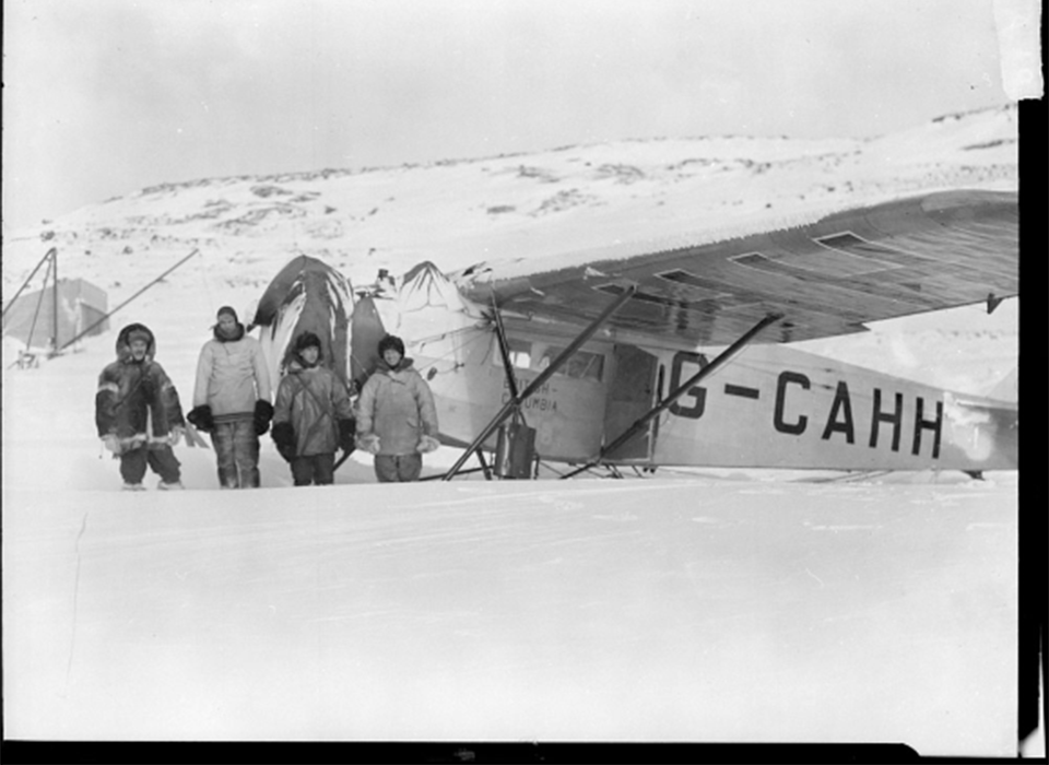 Personnel stand beside an aircraft in one of the Hudson Strait Expedition Base camps.